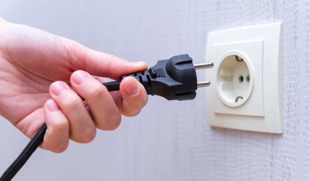 Un om care scoate un cablu din priză