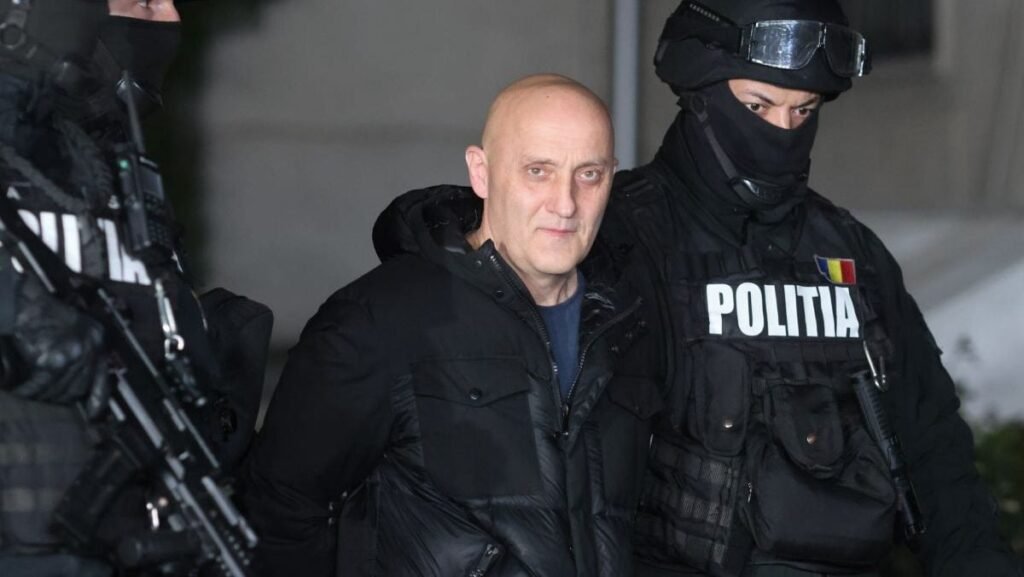 Imagini de noapte cu Horațiu Potra, imbracat in haine negre, este escortat de polițiști mascați în afara sediului IPJ Prahova, în Ploiești, 8 decembrie 2024.