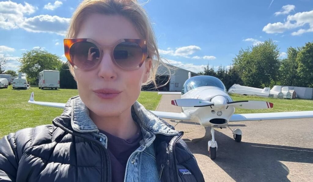Un iPhone 16 Pro a căzut din avion și a „supraviețuit” aventurii. În ce stare a fost găsit apoi de proprietar Selfie cu o femeie în fața unui avion parcat de mici dimensiuni, în fața unei pajiști verzi.