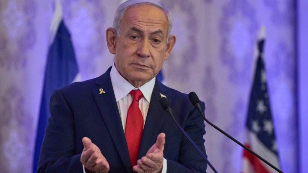 Prim-ministrul israelian Benjamin Netanyahu, în sacou negru, camasa alba si cravata rosie, tine maine in fata, impreunate, si palmele deschise, in timp ce vorbește la o conferință de la Ierusalim, duminică, 27 iulie 2025.