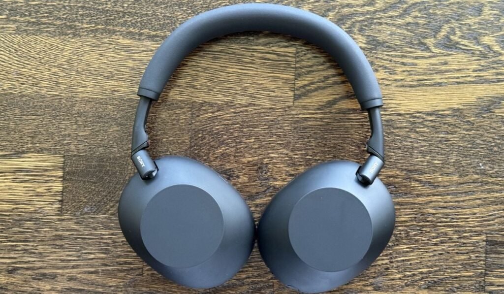 Căștile Sony WH-1000XM6 așezate pe un fundal de lemn.