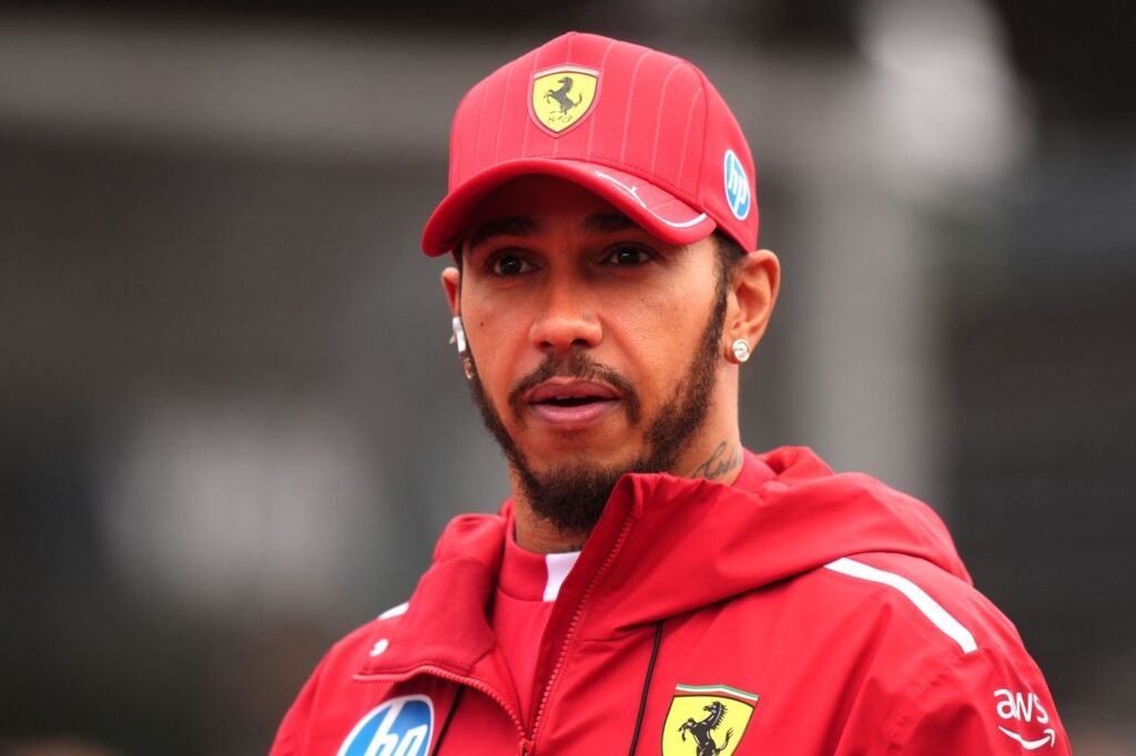Imagine cu Lewis Hamilton purtând o șapcă roșie cu logo-ul Ferrari și o bluză de aceeași culoare