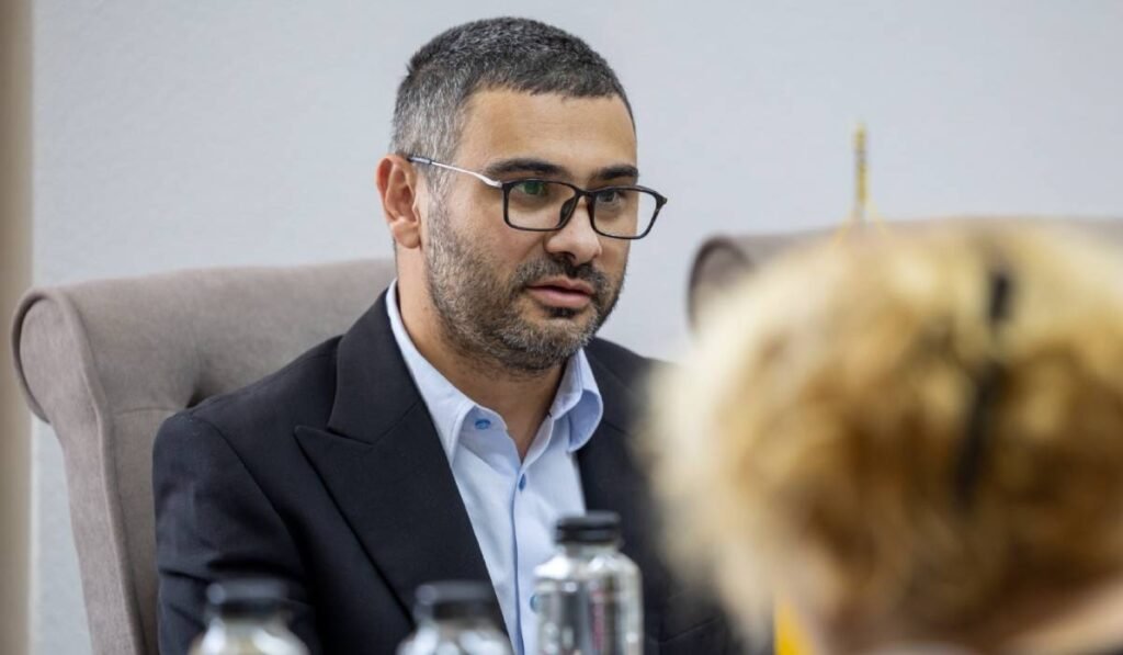 Florin Manole, ministrul Muncii, în timpul unei ședințe, poartă ochelari și vorbește cu angajații din minister