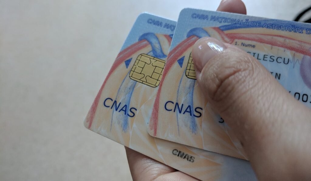 O femeie ține în mână două carduri de sănătate