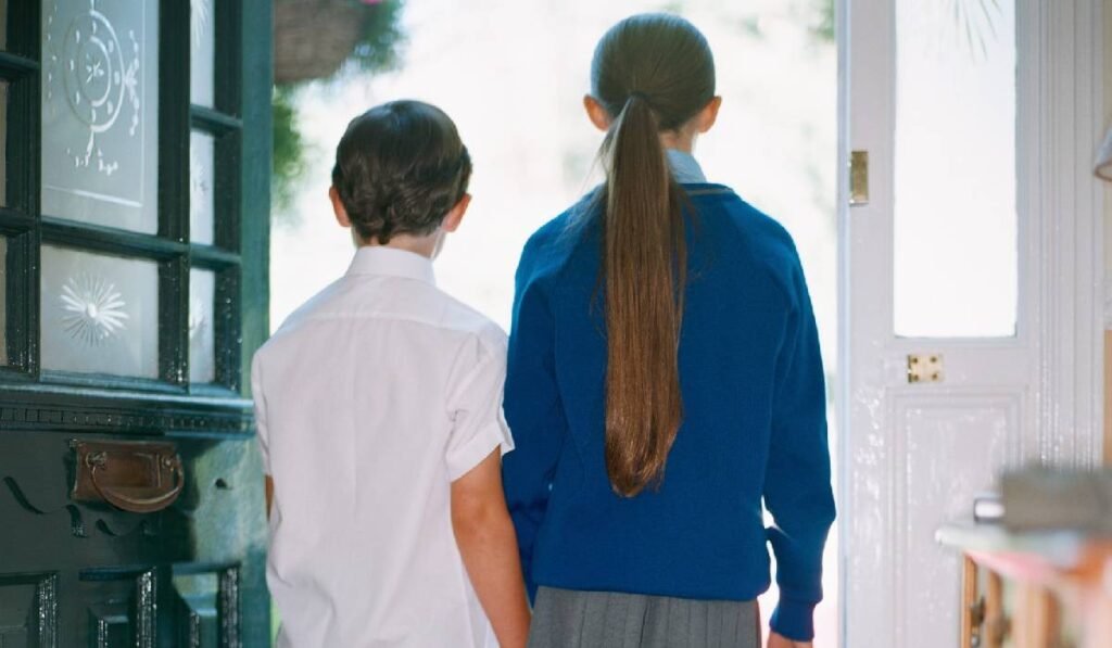 Cornel Ban despre tăierile în educație Doi copii, băiat și fată, cu spatele spre fotograf, pregătindu-se să meargă spre școală