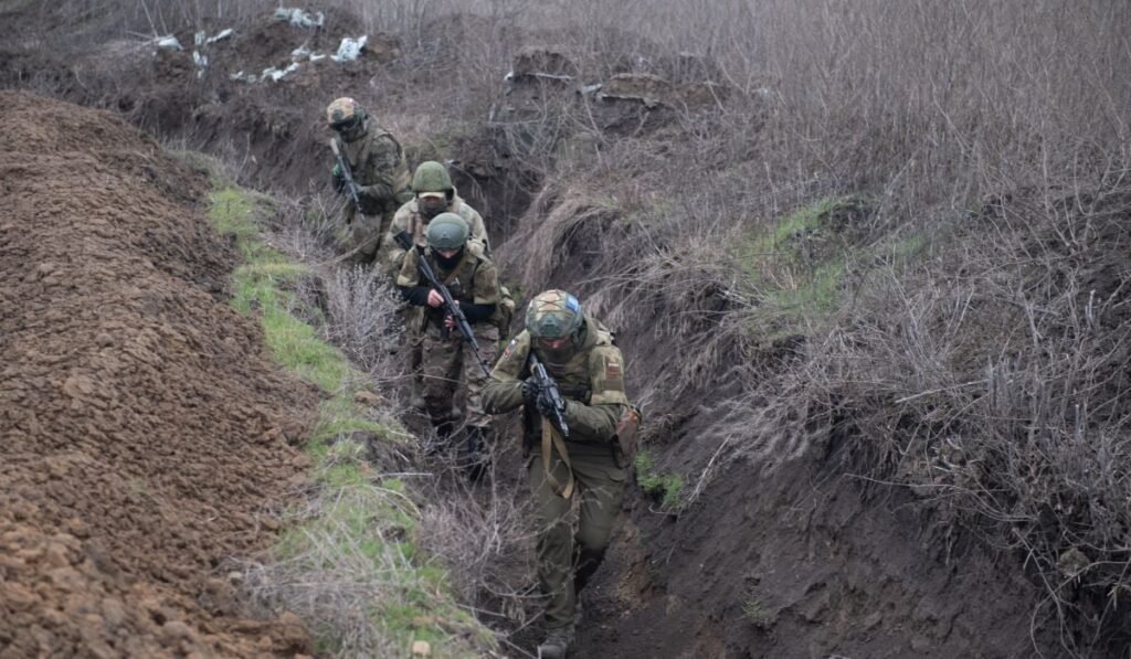 Patru soldați ruși, la linia frontului cu Ucraina, inaintand prin transee cu armele pregatite
