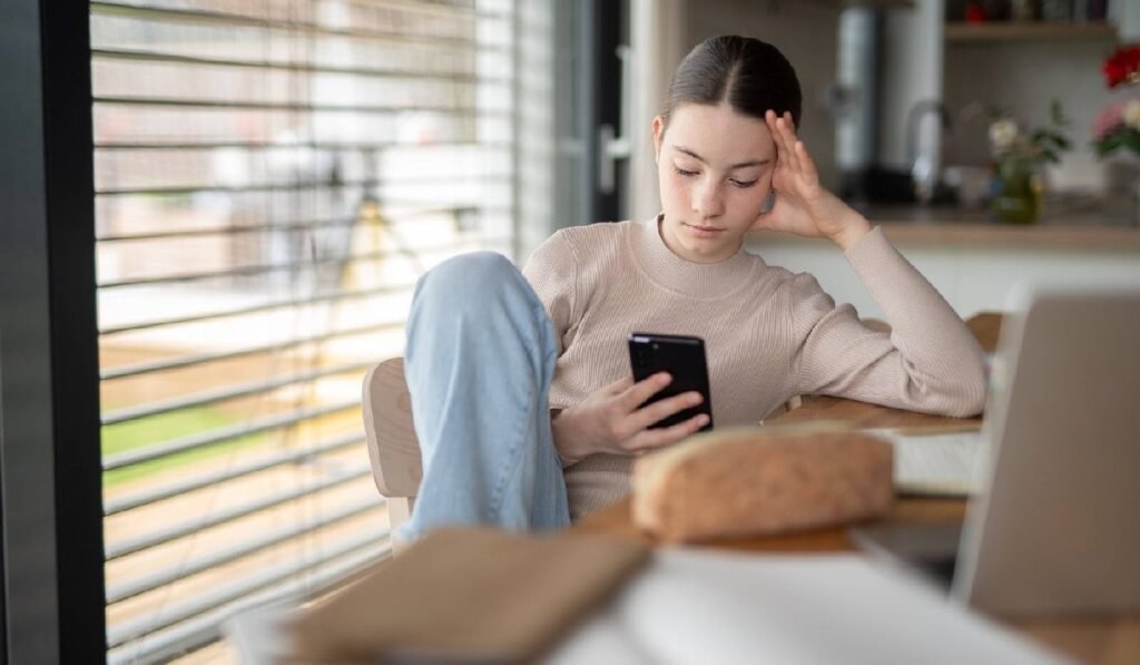 Tinerii din Generația Z preferă să stea închiși în casă. Care este motivul Adolescentă stresată verificându-și telefonul, derulând paginile de social media.