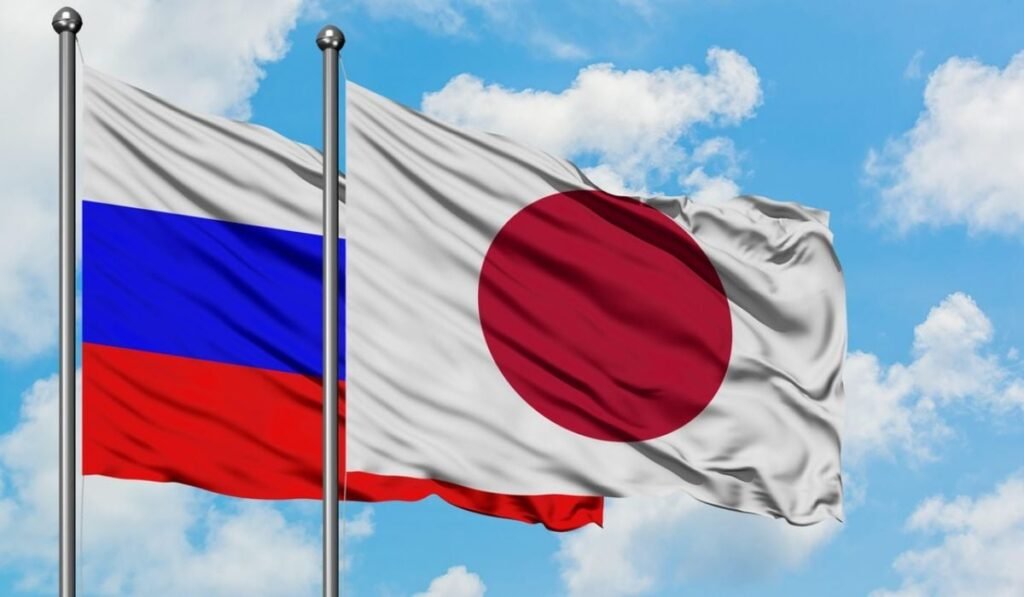 Steagurile Rusiei și Japoniei fluturând în vânt pe un cer albastru înnorat. Concept de diplomație, relații internaționale.