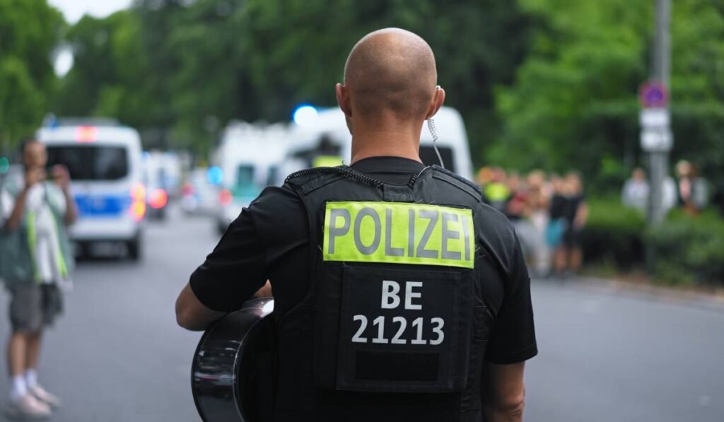 Un polițist german la locul unui accident din Germania, acesta privește spre mulțimea de oameni