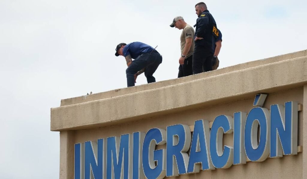 Polițiștii verifică acoperișul unei clădiri din apropierea locului împușcăturilor de la un birou al Imigrării și Vamei din SUA din Dallas. Pe clădire scrie mare Imigrare