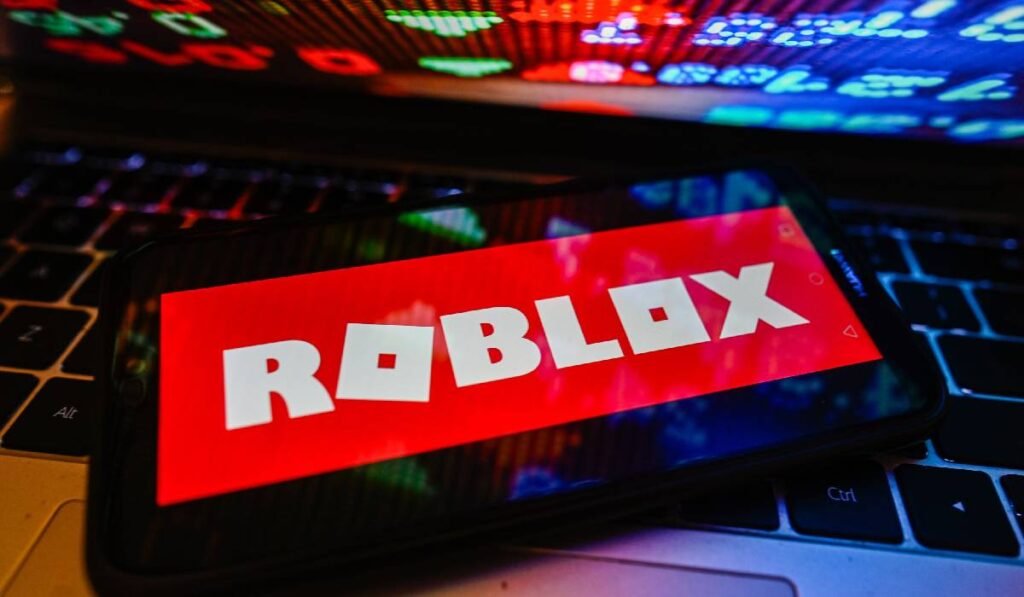 În această ilustrație foto, un logo Roblox este afișat pe un smartphone cu procente de la bursă pe un laptop.