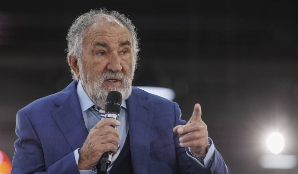 ion tiriac imbracat intr-un sacou albastru in timpul unei conferinte vorbind la un microfon