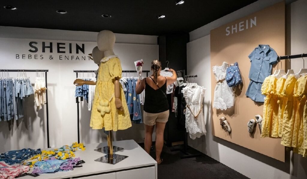 Un client se uită la haine la un magazin pop-up al brandului de modă rapidă Shein, în Dijon, pe 26 iunie 2025.